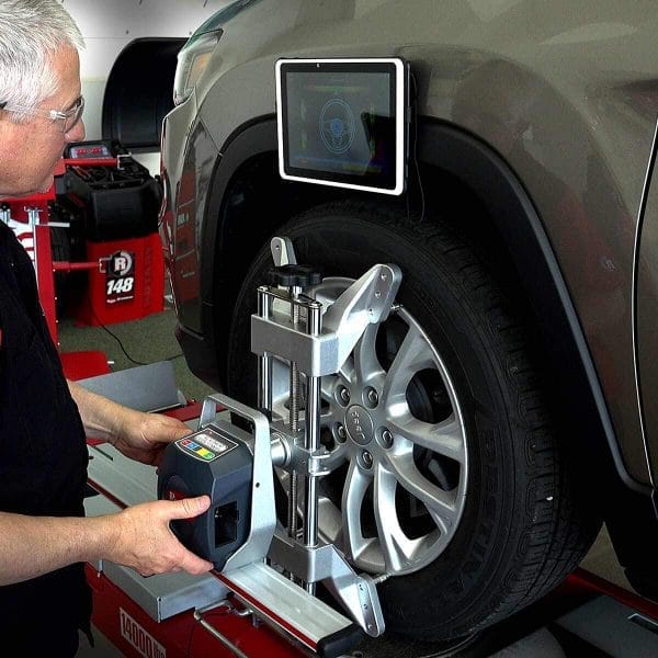 Technician using the R1065 wheel alignment machine on a vehicle